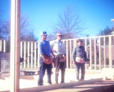 three carpenters with framed walls in the background