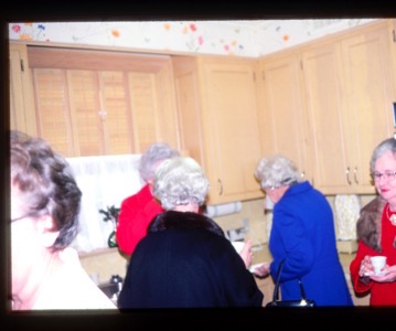 ladies enjoying coffee in the kitchen with cabinets in background